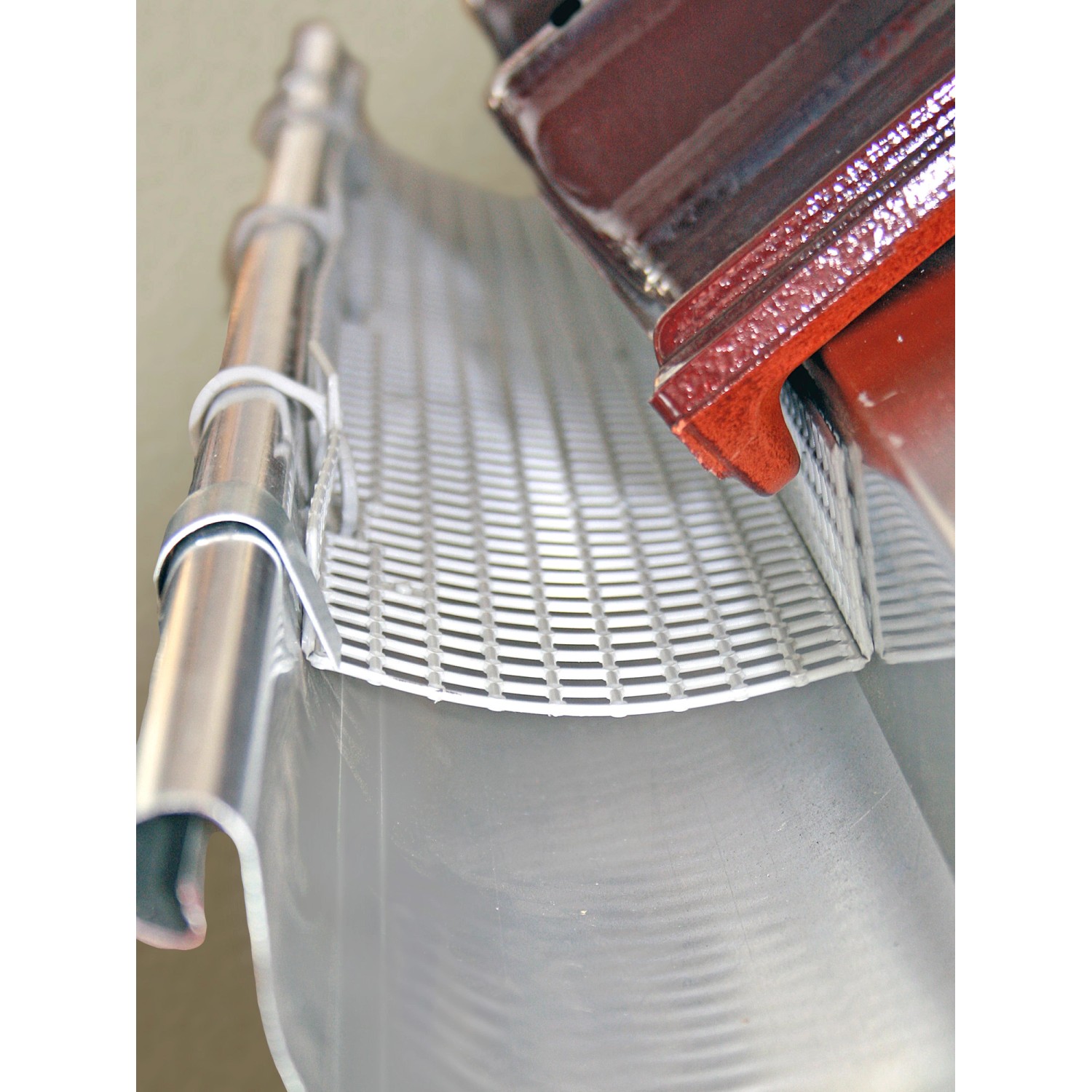 Grauer Sarei Laubstopp aus Polypropylen in einer Metall-Dachrinne.