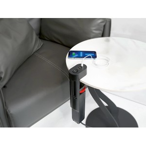 Schwarze 3-fach Steckdosenleiste mit USB-Anschlüssen am Tisch befestigt, ein Smartphone wird geladen.