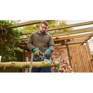 Mann sägt Holz mit Bosch Akku-Kettensäge UniversalChain 18. Kompakte Akku-Kettensäge für Gartenarbeiten.