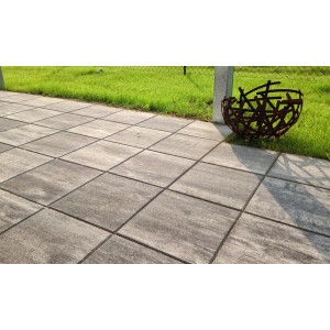 Verlegte, anthrazit-schattierte Terrassenplatten 40x40 cm mit Dekoelement im Garten.