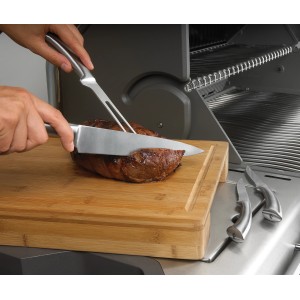 Napoleon Schneidebrett aus Bambus mit Edelstahl-Schalen und Saftrille beim Schneiden von Fleisch.