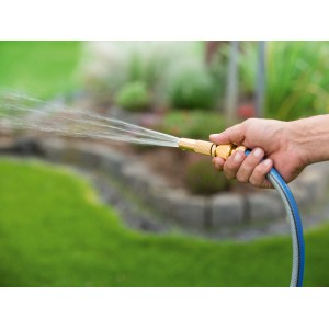 Hand hält LUX Aluminium Anschlussset mit Wasserspritzer. Bewässerung mit Gartenschlauch.