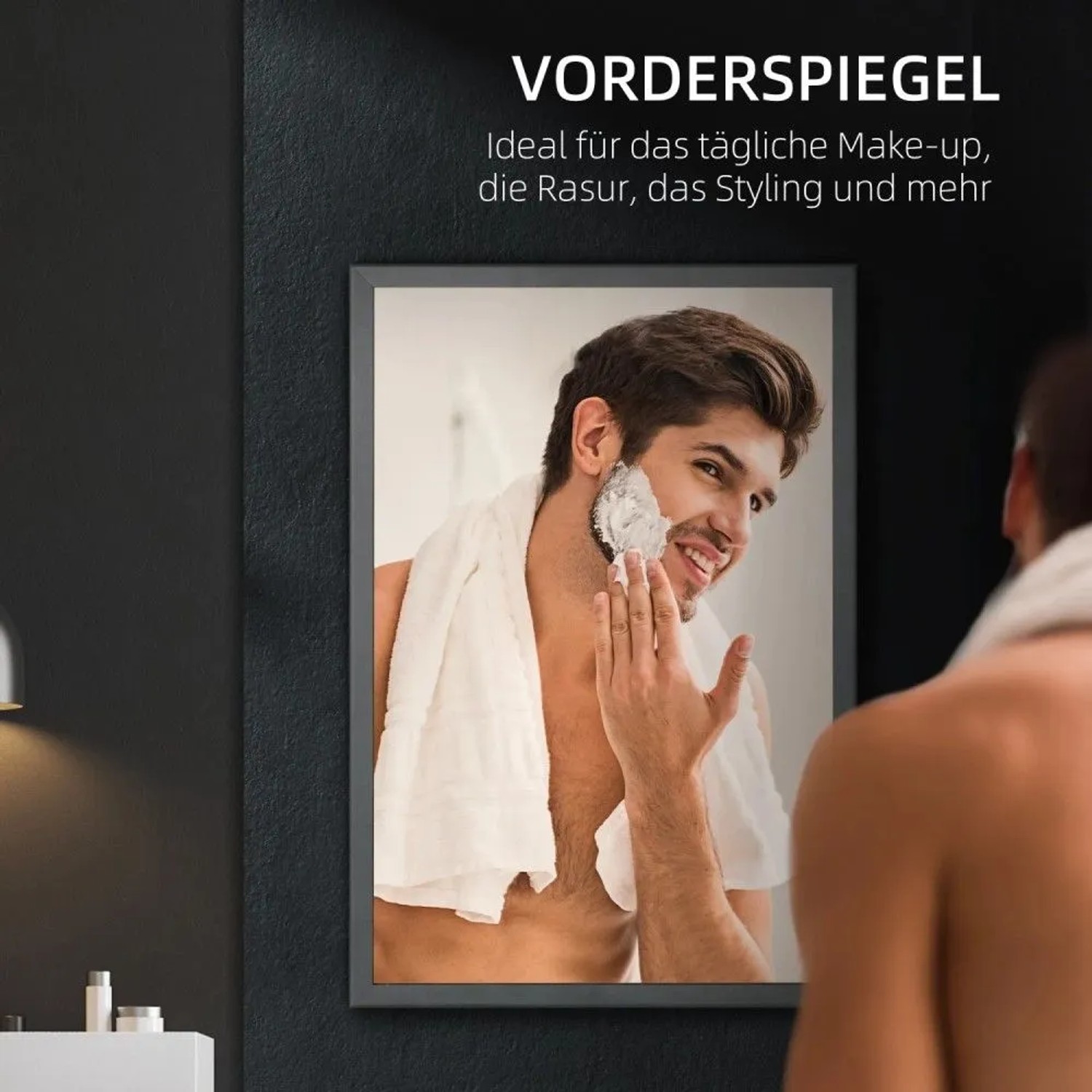 Mann rasiert sich lächelnd im Spiegel eines schwarzen Spiegelschranks im Badezimmer.