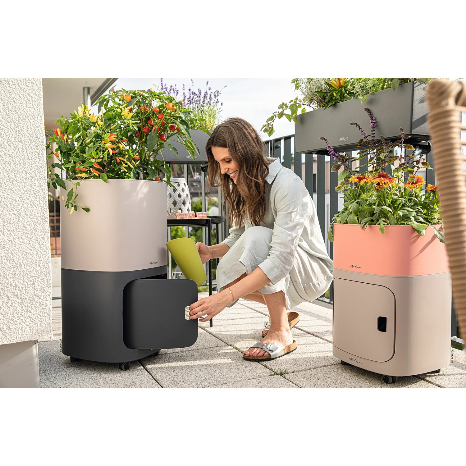 Lechuza Pila Color Storage in Sandbraun mit Aufbewahrungselement und Frau auf Balkon.