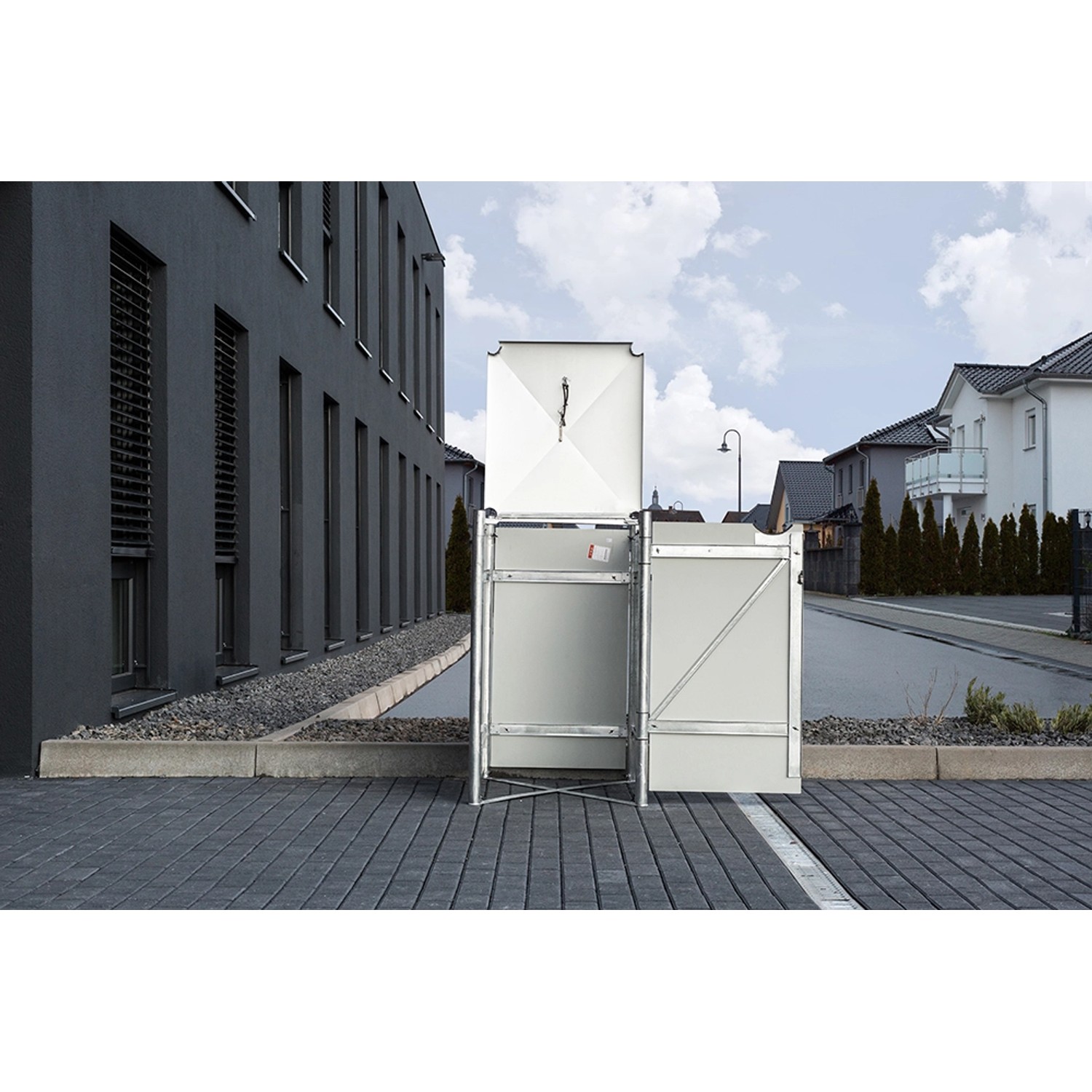 Schwarze Hide Mülltonnenbox aus Kunststoff, 81x70x116 cm, mit geöffnetem Deckel vor einem Wohnhaus.