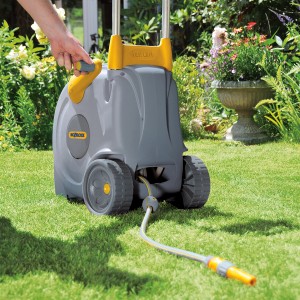 Hozelock Schlauchwagen Fast Cart mit 40 m Schlauch im Garten, mit Hand am Griff.