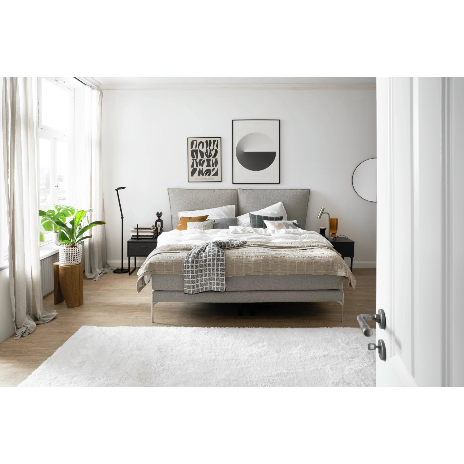 Schlafzimmer mit Bett, Teppich und Gardinen. Helle, freundliche Atmosphäre.