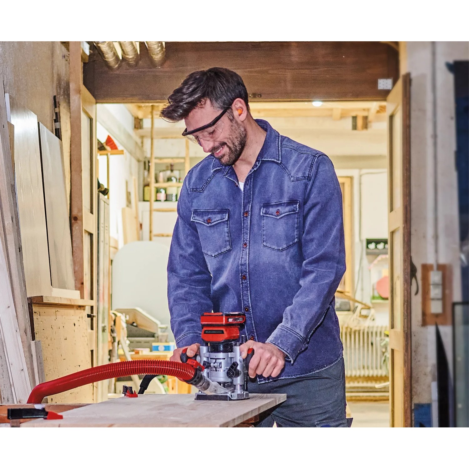 Mann arbeitet mit Einhell Akku-Oberfräse TP-RO 18 Li BL an Holz.