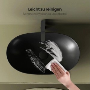 Hand reinigt ovales Emke Aufsatzwaschbecken aus mattschwarzer Keramik. Schmutzabweisende Oberfläche im Bad.
