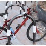 Basi Faltschloss ZR 314 sichert rotes Fahrrad am Ständer. Stahlglieder mit Kratzschutz-Ummantelung für Diebstahlschutz.