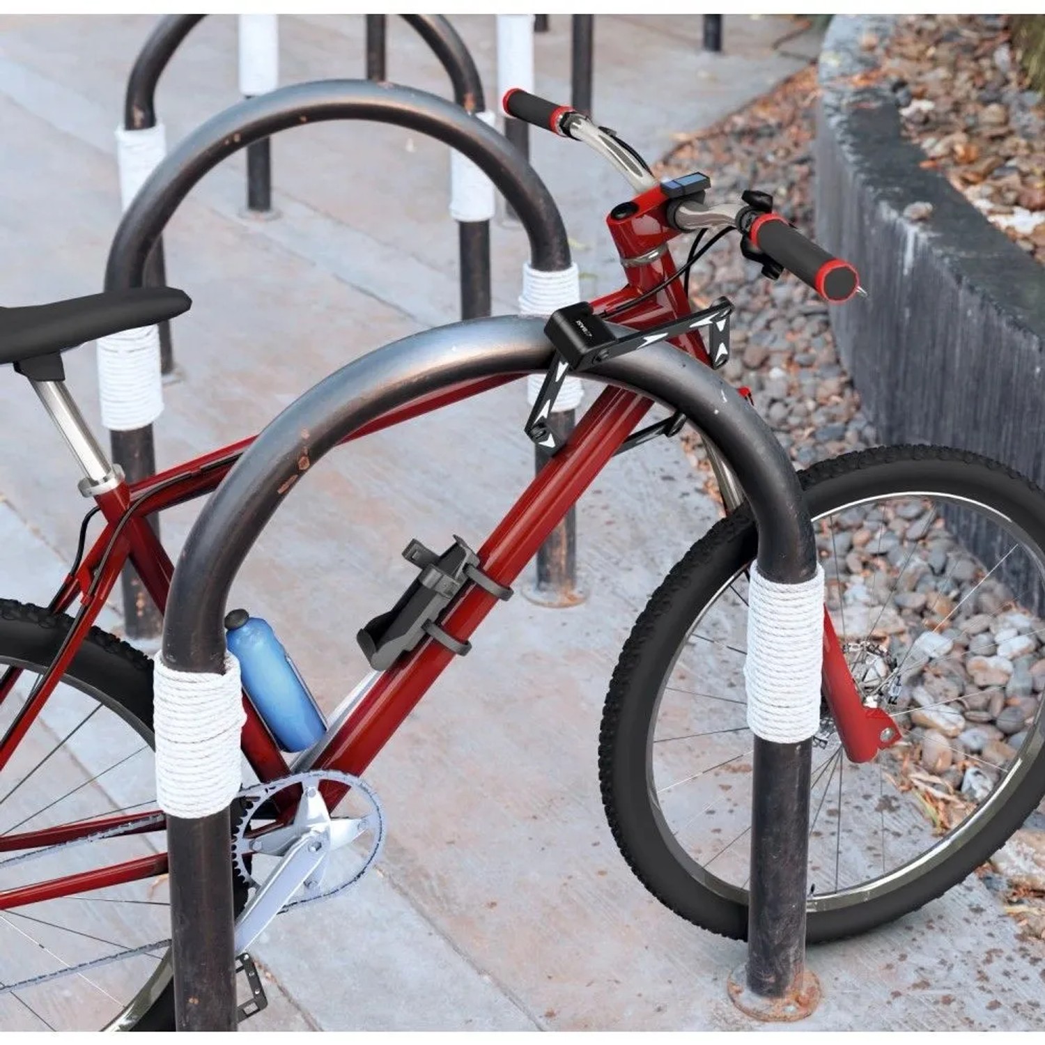 Basi Faltschloss ZR 314 sichert rotes Fahrrad am Ständer. Stahlglieder mit Kratzschutz-Ummantelung für Diebstahlschutz.