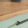 Detailaufnahme: Respekta Küchenzeile Anton Landhaus in Schilfgrün mit Arbeitsplatte in Wildeiche-Optik.