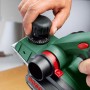Bosch Hobel PHO 3100: Hand justiert Hobeltiefe am grünen Elektrohobel.