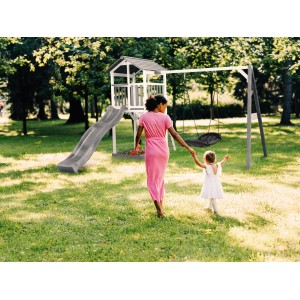 Axi Beach Tower Spielturm mit Nestschaukel und Rutsche im Garten mit Mutter und Kind.