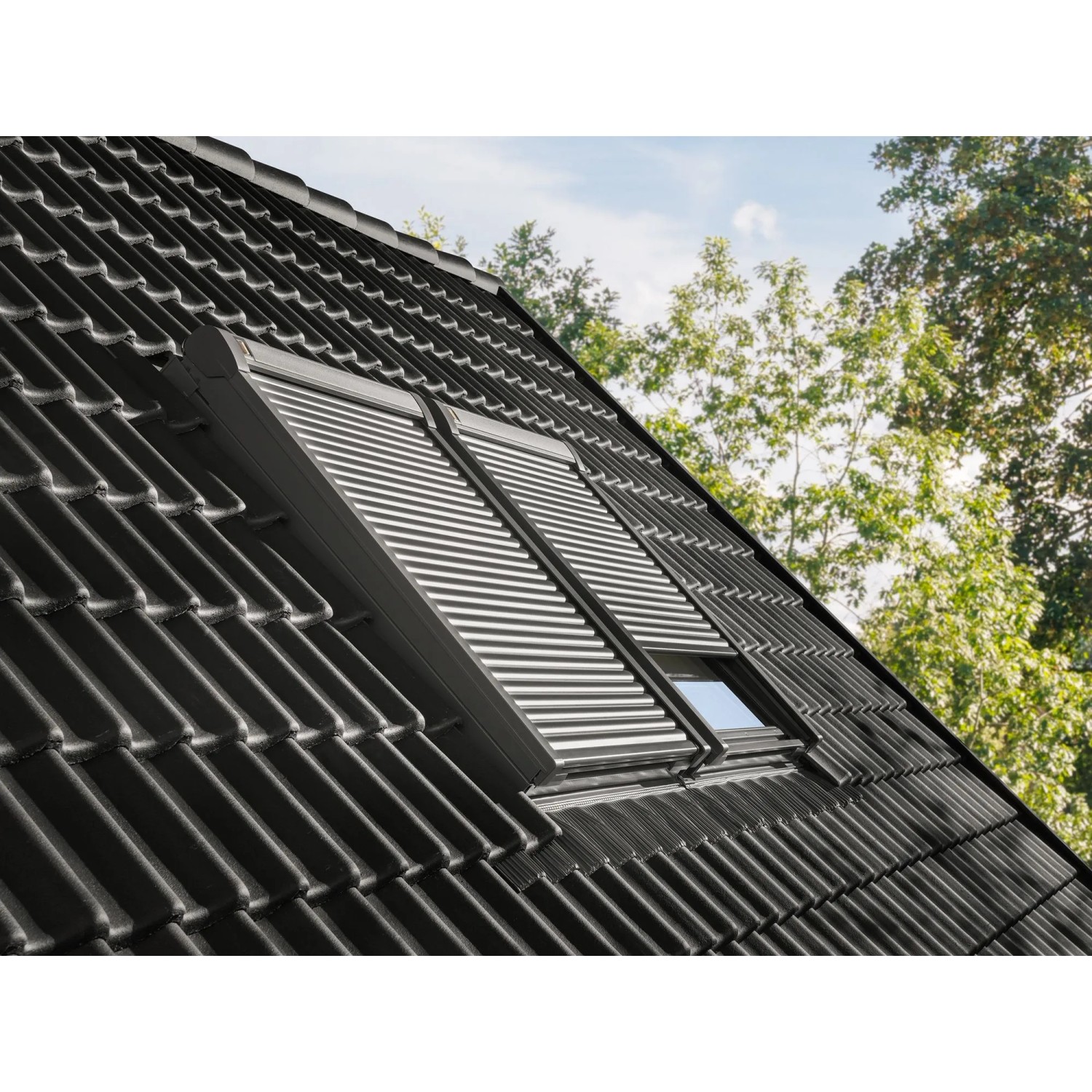 Dachfenster mit geschlossenem, elektrischem Rolladen ElektroModular CK04 Alu auf einem Dach.