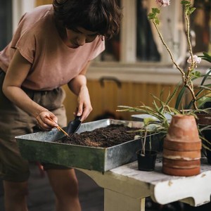 Frau benutzt Fiskars Pflanzkelle Solid zum Pflanzen in Erde. Gartenhandgerät für Aussaat und Umtopfen.