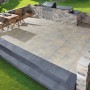Premac Blockstufe Anthrazit (50x35x15 cm) als Treppe zu einer Terrasse mit Grillplatz.