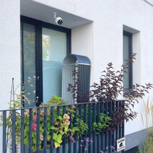 Weiße Kamera Attrappe mit Blinklicht an Hauswand, Sicherheitstechnik für den Außenbereich.