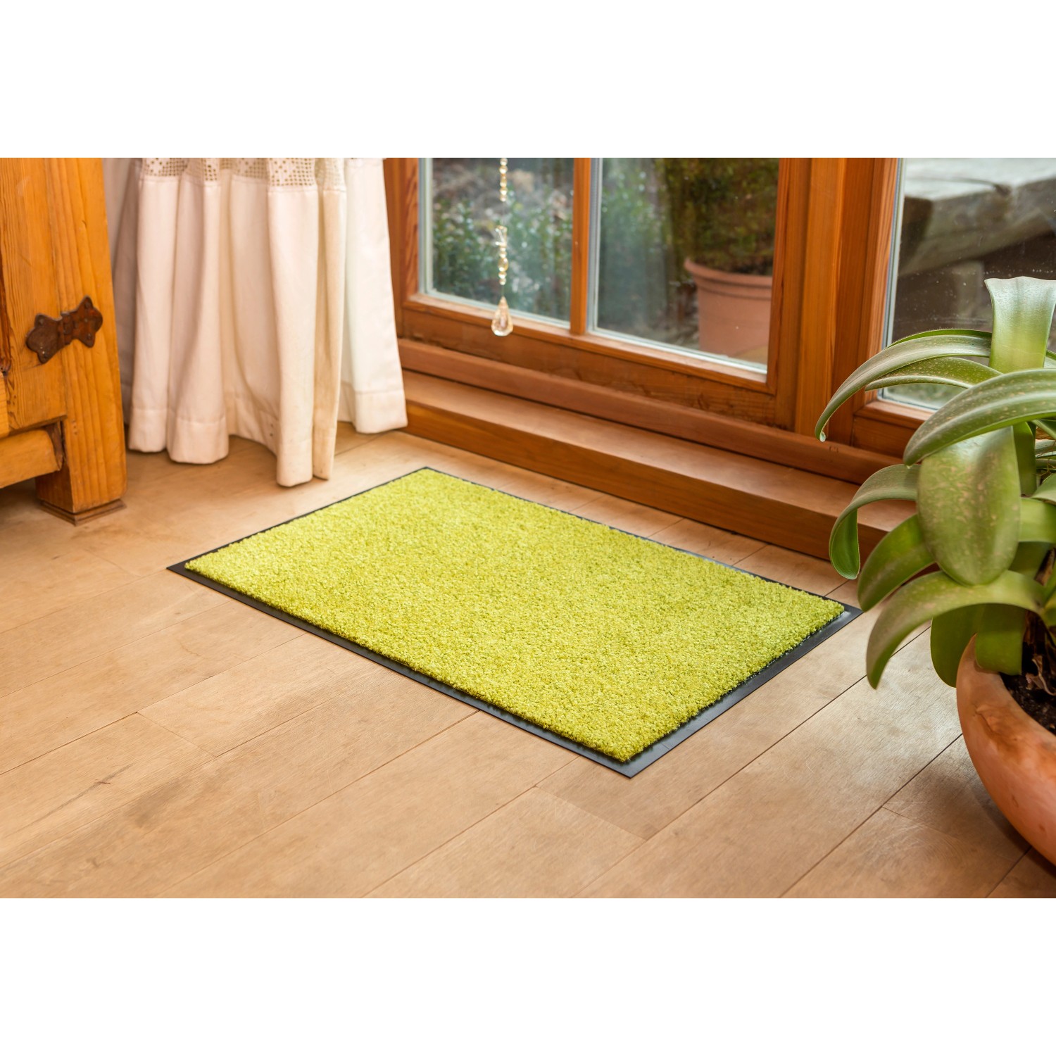 Grüne Astra Sauberlaufmatte Proper Tex Uni, 60x180 cm, vor Fenster auf Holzboden.