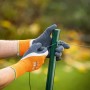 Hände mit LUX Arbeitshandschuhen Super Grip Gr. 8 beim Drahtziehen an einem Zaunpfahl.