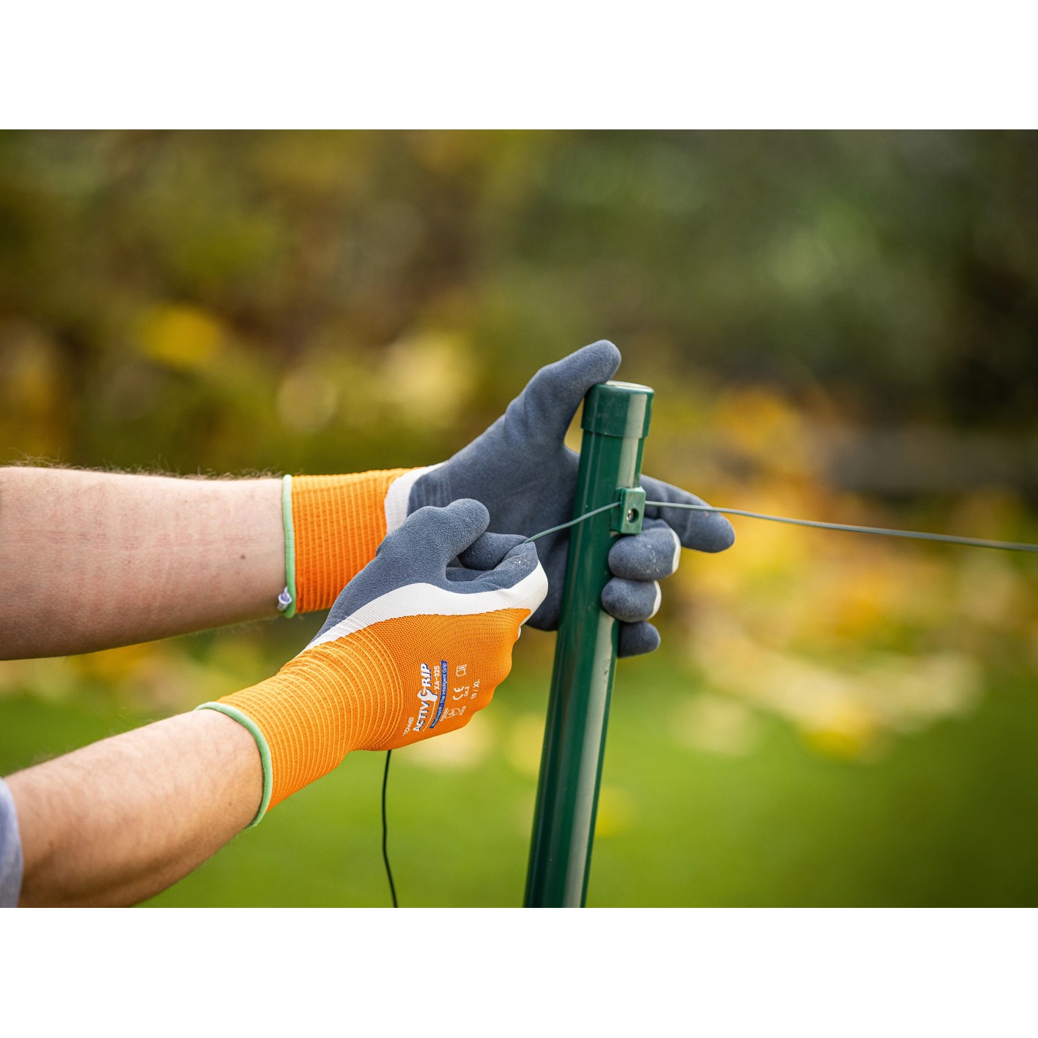 Hände mit LUX Arbeitshandschuhen Super Grip Gr. 8 beim Drahtziehen an einem Zaunpfahl.