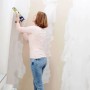 Frau dichtet Risse an einer Wand mit Soudal Maleracryl Weiß ab. Ideal für Fugen und Anschlüsse, überstreichbar.