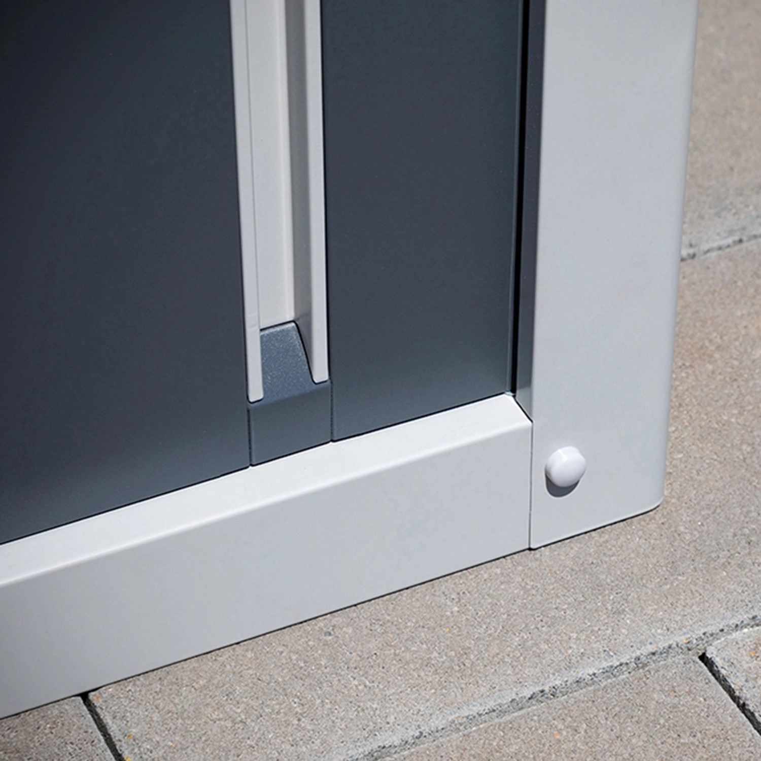 Detailaufnahme: Trimetals Geräteschuppen Guardian, graue Schiebetür, Stahlrahmen und Boden.