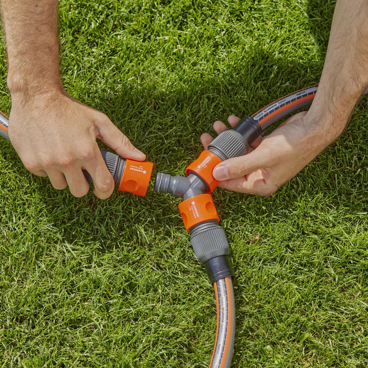 Gardena Profi-System Y-Stück für Schlauchabzweigung im Garten, montiert von zwei Händen.