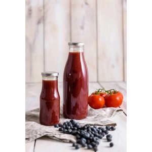 Dr. Oetker Smoothie Flasche (750ml) aus Glas, gefüllt mit rotem Smoothie, neben Blaubeeren und Tomaten.