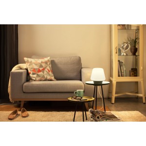 Philips Hue Wellness Tischleuchte in Schwarz, mit Dimmschalter, auf Beistelltisch im Wohnzimmer.