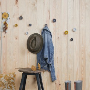 Wandhaken Tulip gelb von Wagner, Elastomer und Stahl, an Holzwand mit Jacke und Hut.