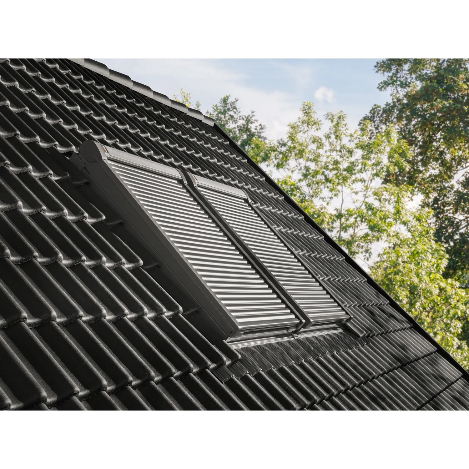 Dachfenster mit geschlossenem, elektrischem Alu-Rolladen ElektroModular CK04 auf einem Dach.