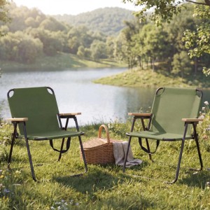 Zwei grüne Klapp-Campingstühle mit Bambus-Armlehnen und Metallgestell im Grünen am See. Für Camping, Garten, Balkon.