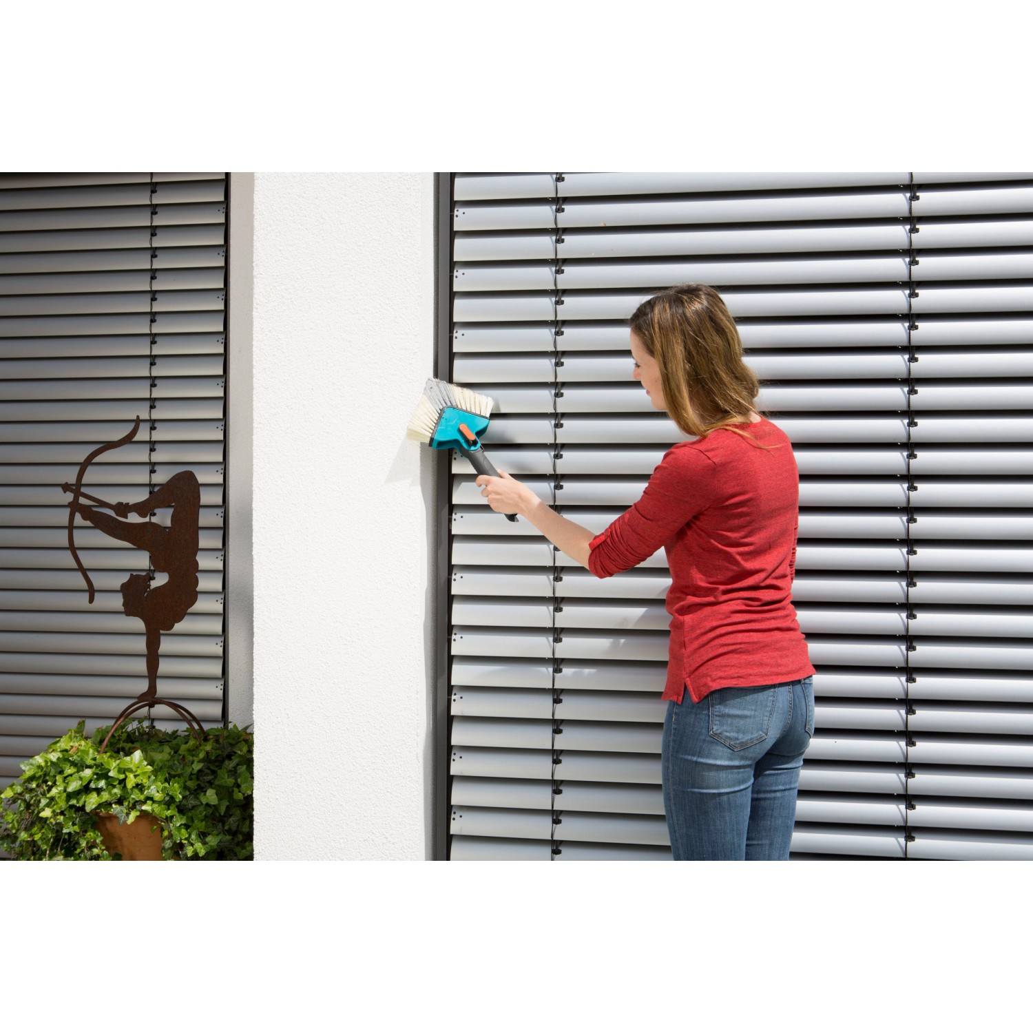 Frau reinigt Jalousie mit Gardena combisystem Winkelbesen. Der Winkelbesen ist ideal für Ecken und Winkel.