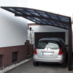 Mattbrauner Ximax Carport Portoforte-80 mit Auto. Moderner Metall-Carport mit gebogenem Dach.