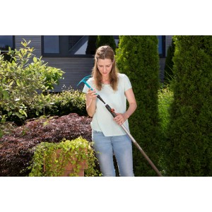 Frau montiert Gardena combisystem-Kleinhäckchen mit 3 Zinken an einen Stiel im Garten.
