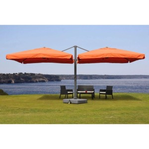 Großer MCW Doppel-Ampelschirm T44 Terracotta mit Ständer auf Rasen am Meer. Bietet Schatten für Gartenmöbel.