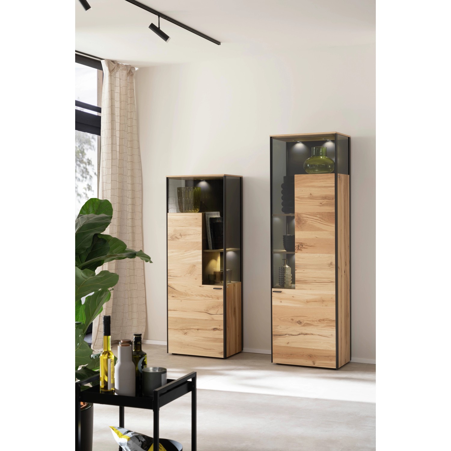 Zwei Schöner Wohnen Vitrinen Emilia mit Glas und Holzoptik im Wohnzimmer.