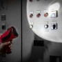 Eufab LED Handscheinwerfer 3W in Rot/Schwarz leuchtet Schaltschrank aus, gehalten von Hand.
