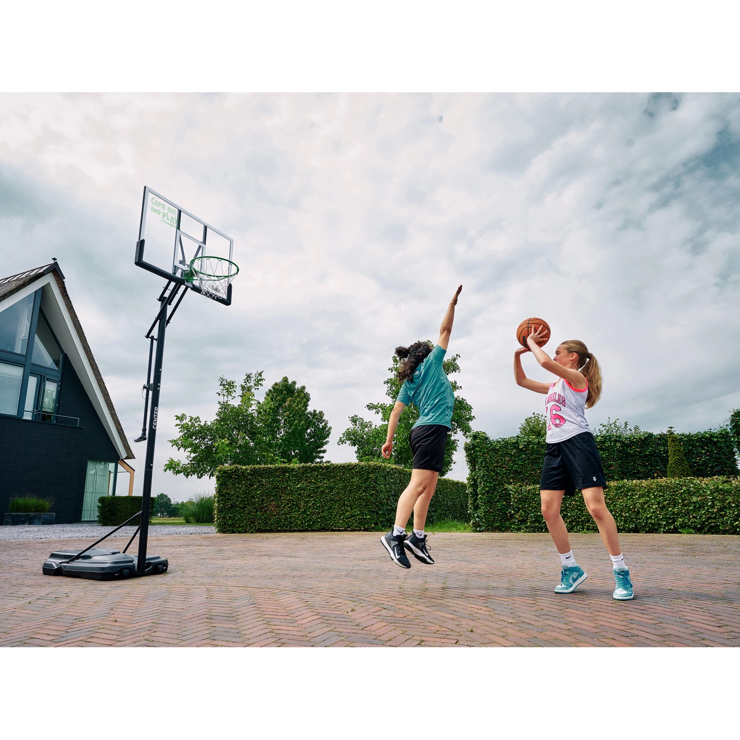 Salta Basketballständer Center mit zwei spielenden Personen im Garten.
