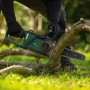 Bosch Akku-Kettensäge PKE18V-30-28 beim Sägen eines Astes im Garten.