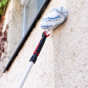 Malerset mit Teleskopstab im Einsatz: Farbrolle streicht helle Rauwand. Ideal für Renovierung.