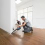 Mann saugt mit Bosch Akku-Handstaubsauger GAS 18 V-1 Solo Staub an einer Wand. Handlicher Akkusauger.