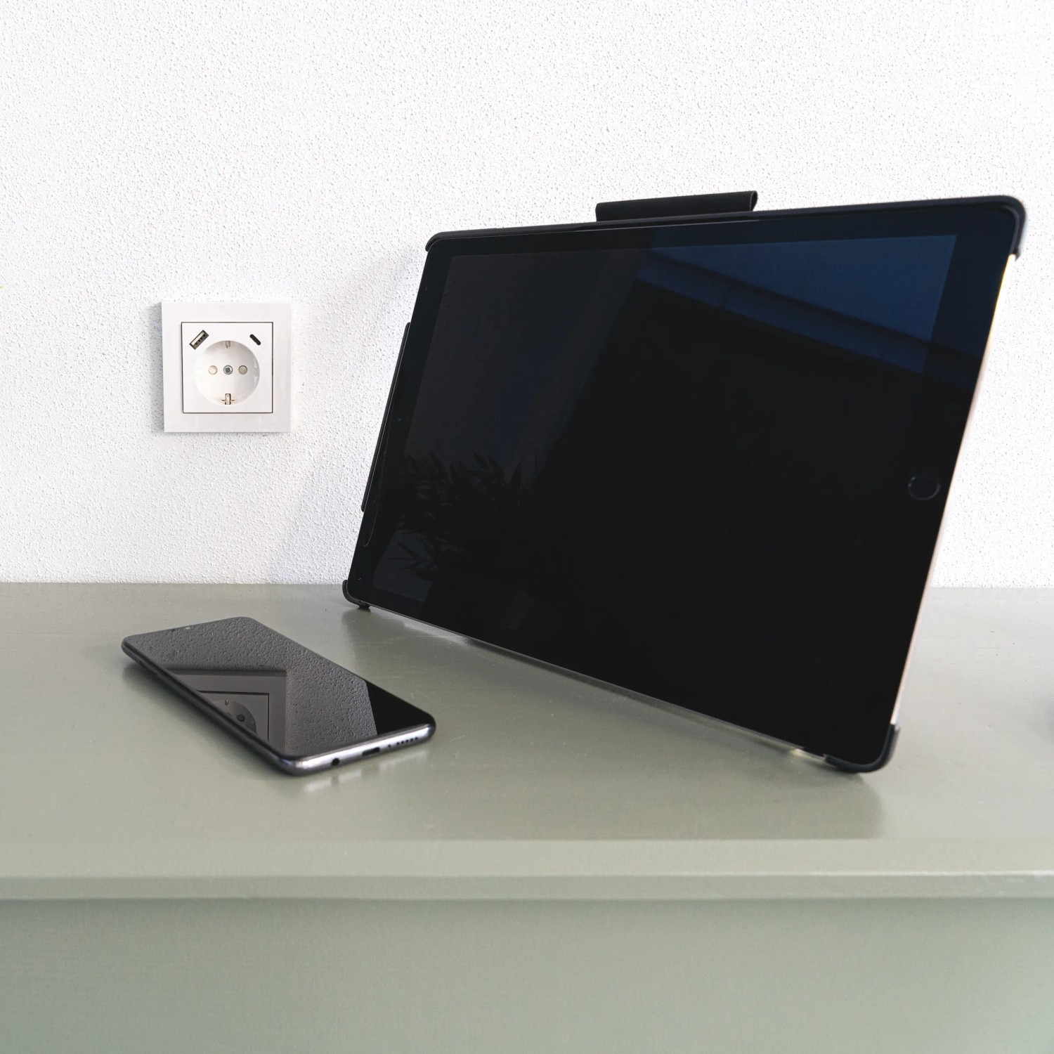 Weiße ProCharge Steckdose mit USB-A und USB-C Anschluss neben Tablet und Smartphone.