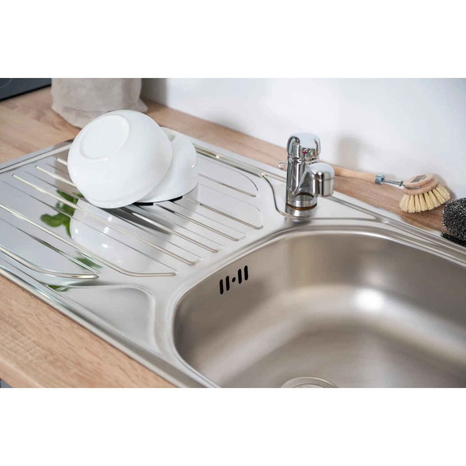 Spüle aus Edelstahl mit Abtropffläche, Geschirr und Armatur. Passend zur Respekta Economy Küchenzeile.