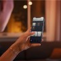 Frau steuert Philips Hue Luster E14 Lampen per App.