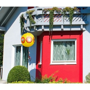 Gardigo Vogelabwehr Ballon 2er Set vor Hauswand. Gelber Ballon mit Augenmuster und Flatterbändern.
