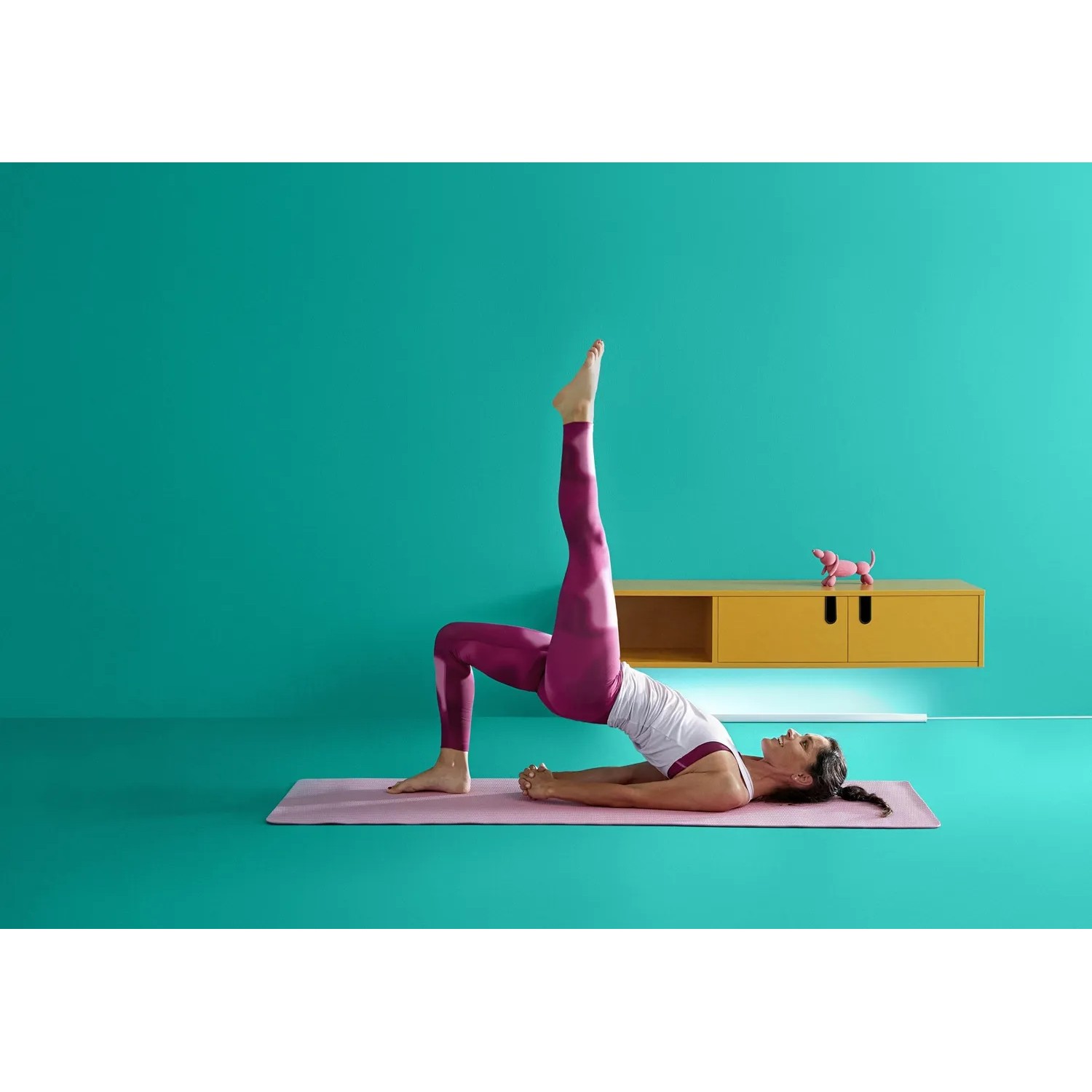 Frau macht Yoga mit WiZ LED Stehleuchte im Hintergrund, die farbiges Licht an die Wand wirft.