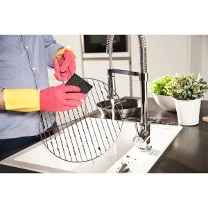 Mann reinigt Grillrost mit Vileda Haushaltshandschuhen Der Robuste Protection M in Gelb/Pink.