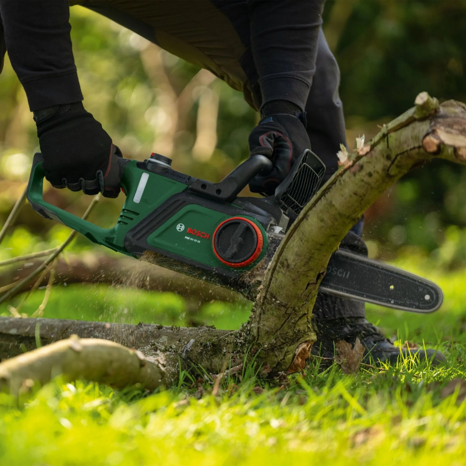Bosch Akku-Kettensäge PKE18V-30-28 Solo im Einsatz beim Sägen eines Astes.